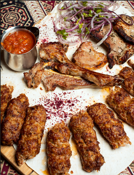 Layali Riyadh signature mixed grill platter featuring lamb chops, seekh kebabs, and grilled steak served with sumac onions and spicy dipping sauce