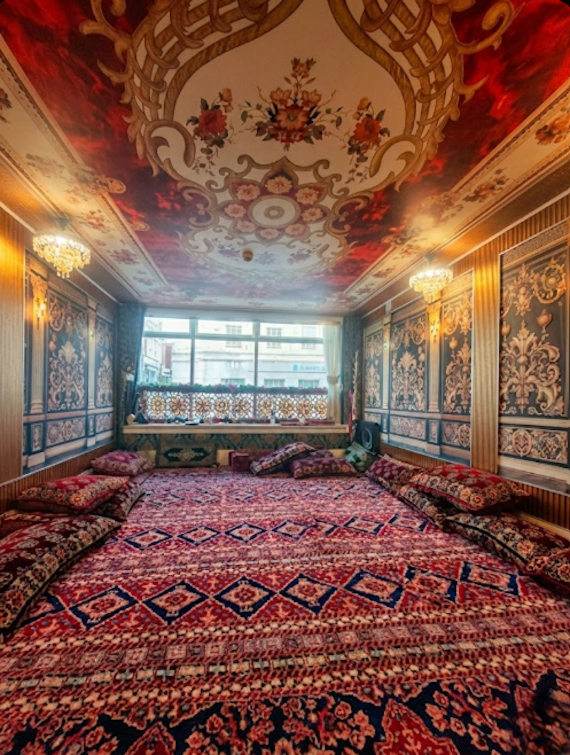 Exotic Arabian-style restaurant interior at Layali Riyadh, showcasing authentic floor seating with red patterned rugs and cushions, ornate wall art, and warm lighting for a cozy, experiential dining atmosphere